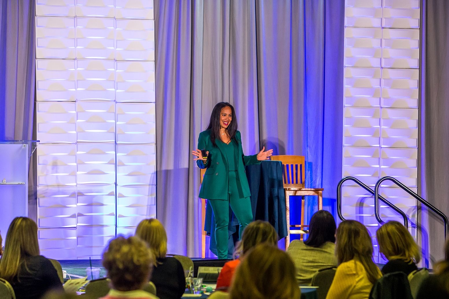 Kelli Williams speaking on stage in a green suit